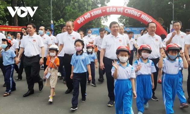 Deputi Harian PM Truong Hoa Binh berjalan kaki untuk menggerakkan seluruh rakyat memakaikan helm pada anak-anak