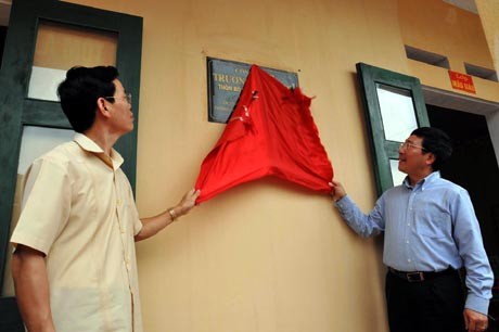 Deputi Perdana Menteri Pham Binh Minh memasang papan penyerahan sekolah kepada pelajar miskin