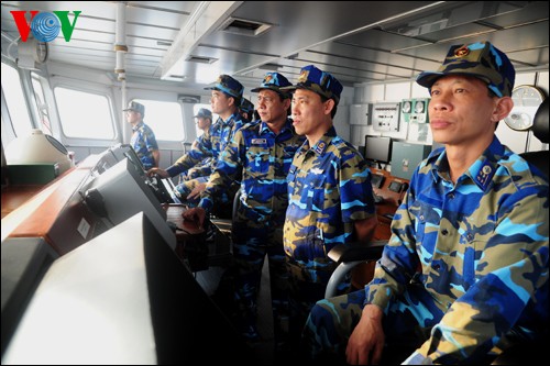 Vietnamese marine police and patrol forces stand side by fishermen 