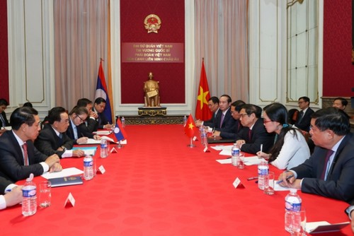PM Pham Minh Chinh meets Lao counterpart, Vietnamese community in European countries   - ảnh 1